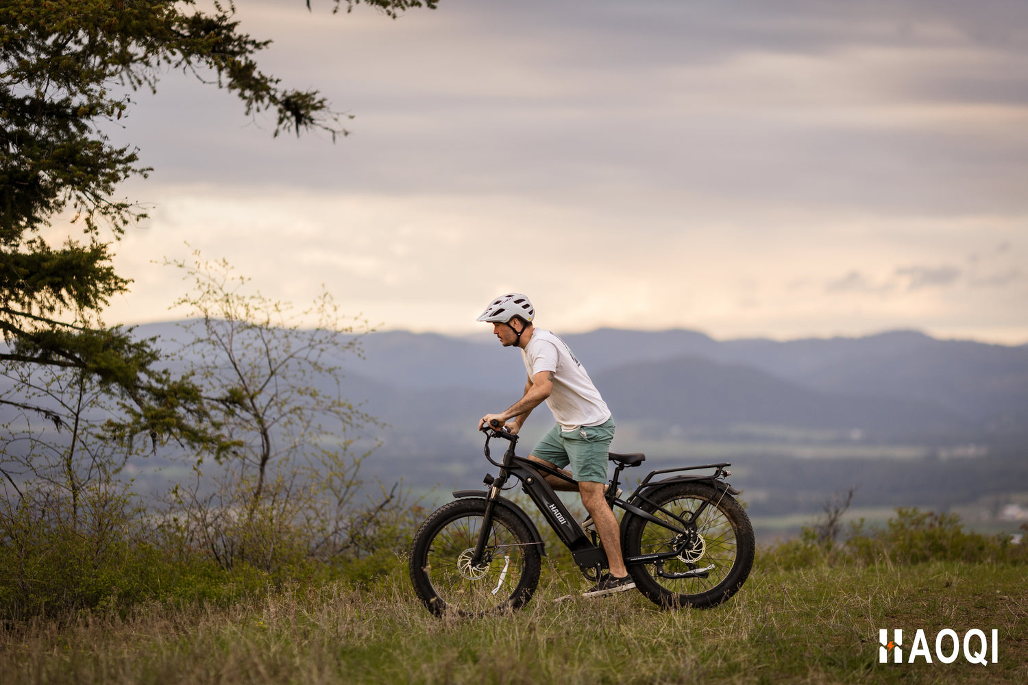 A person riding the HAOQI Eagle electric bicycle on a scenic trail, demonstrating its fat tire stability and fitness capabilities.