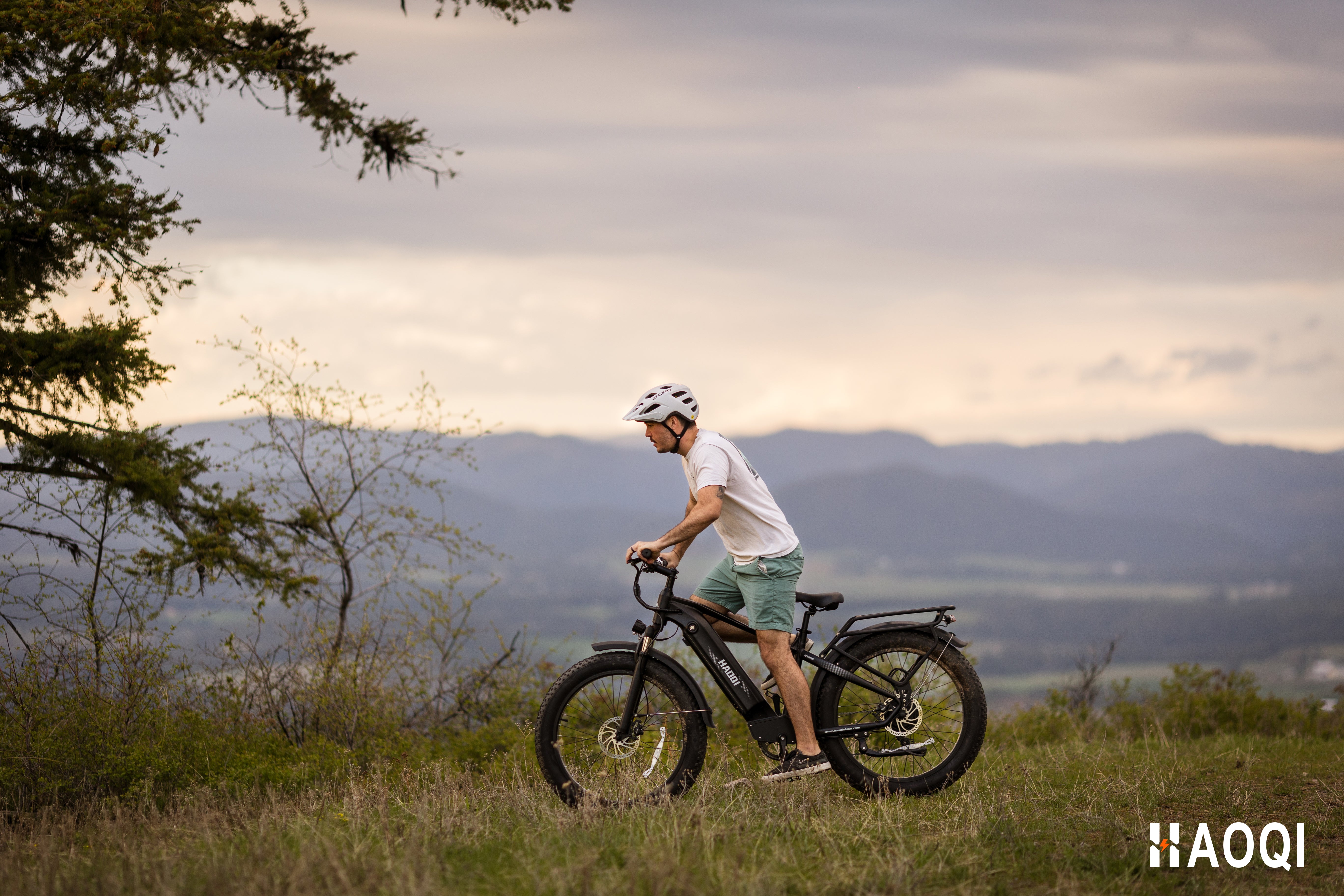 A person riding the HAOQI Eagle electric bicycle on a scenic trail, demonstrating its fat tire stability and fitness capabilities.